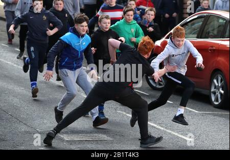 I ragazzi si sfidano per la palla di pelle durante l'evento di gioco annuale di Jedburgh Ba' su High Street di Jedburgh nei confini scozzesi. Data dell'immagine: Giovedì 27 febbraio 2020. L'evento annuale è iniziato nel 1700 e il primo gioco in assoluto è stato presumibilmente giocato con la testa di un inglese. Coinvolge due squadre, gli Uppies (residenti dalla parte superiore di Jedburgh) e i Doonies (residenti dalla parte inferiore di Jedburgh) che ottengono la palla o alla parte superiore o inferiore della città. La palla, realizzata in pelle, imbottita di paglia e decorata con nastri che rappresentano i capelli, viene gettata nella Foto Stock