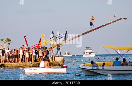 'Festa di San Giuliano' Che Corre su un palo ingrassato per raccogliere una bandiera Foto Stock