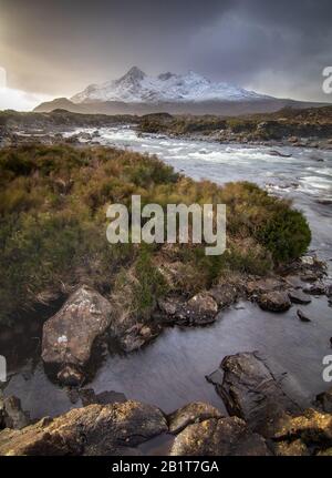 Bagliore dalle tempeste sulle Black Cuillin Mountains, con il fiume Sligachan che corre verso di noi. Preso a Sligachan, Isola di Skye, Scozia. Foto Stock