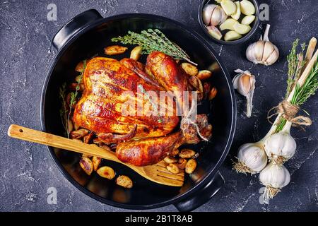 40 spicchi di pollo in una teglia nera su un tavolo in cemento con aglio e timo, vista orizzontale dall'alto, piatto, primo piano Foto Stock