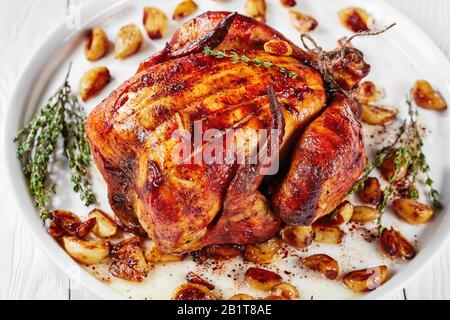 Pollo arrosto con Quaranta Chiodi Di Garlic su un piatto bianco, su un tavolo di legno, cucina francese, vista orizzontale dall'alto, primo piano Foto Stock