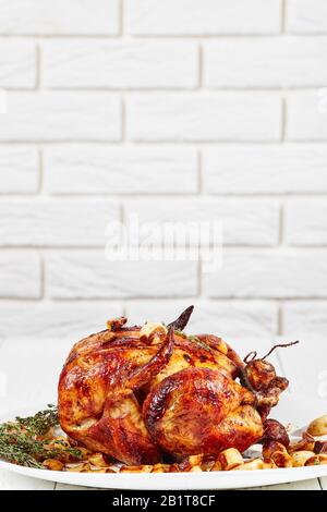 Pollo arrosto con Quaranta Chiodi Di Garlic, pollo 40-Clove su un piatto bianco, su un tavolo di legno con una parete di mattoni bianchi sullo sfondo, french cu Foto Stock