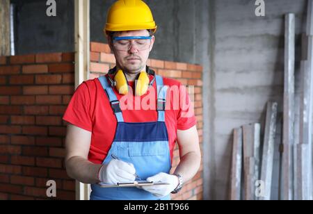 Ispettore di costruzione maschio pensivo che fa note Foto Stock