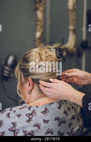 le mani di uno stilista o parrucchiere che styling i capelli della donna in un salone dei capelli Foto Stock