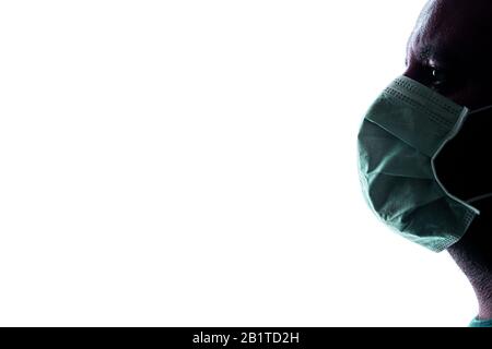 Silhouette di uomo con maschera antivirus per uso medico con retroilluminazione bianca Foto Stock