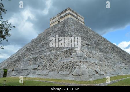 Una vista dall'angolo basso di El Castillo, l'antica piramide maya a gradoni a Chichen Itza in Messico, che sorge sotto un cielo nuvoloso. Foto Stock