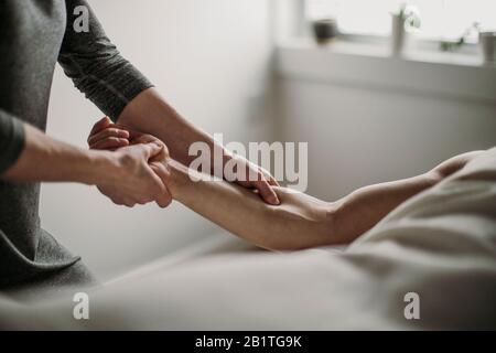 primo piano del terapista del massaggio che tratta il bicep del paziente Foto Stock