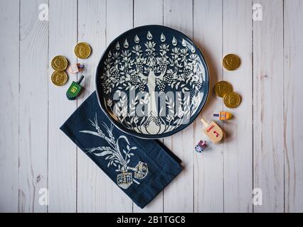 Piatto, draghe e monete di cioccolato decorative Hanukkah su legno bianco. Foto Stock