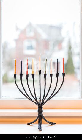 Menorah con candele silluminate per celebrazioni Hanukkah in una finestra. Foto Stock