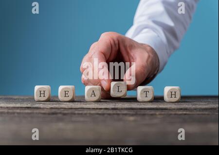 Mano maschile che monta un segno di salute scritto su cubi di legno. Foto Stock