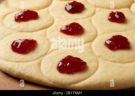 Preparazione di ciambelle farcite con marmellata di fragole da pasta di lievito arrotolata, da vicino Foto Stock