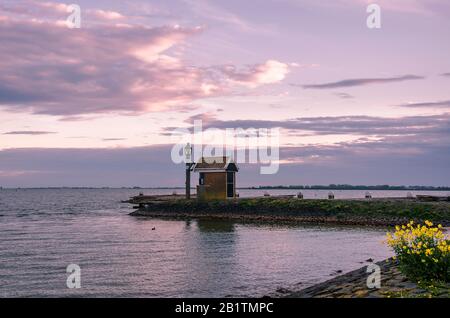 Tramonto sul molo, Volendam, Paesi Bassi. Bella alba in tonalità rosa sull'acqua e silhouette di capanna piccola. Crepuscolo sul lago. Foto Stock