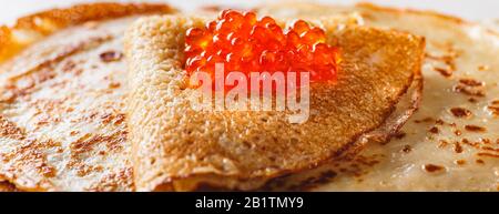 Tradizionale Crepes russo Blini stacked in un piatto con caviale rosso su sfondo chiaro. Maslenitsa tradizionale pasto del festival russo. Cibo russo, r Foto Stock