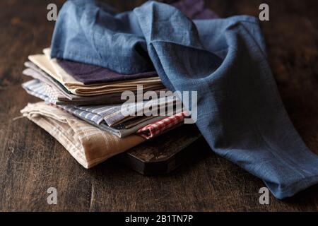 Pile di tovaglioli di lino tessile di vari colori su sfondo scuro. Concetto di Dshcloth Foto Stock