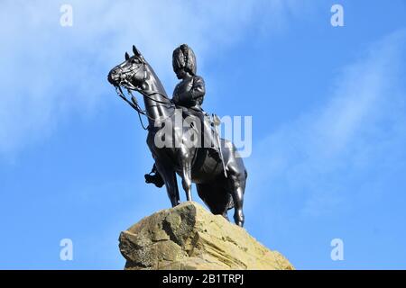 Statua commemorativa pubblica di Royal Scots Grays, un reggimento di cavalleria. Statua di soldato a cavallo. Sulla cima di una roccia con sfondo blu cielo da sotto. Foto Stock