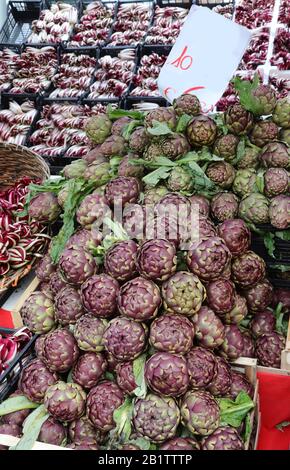 Stalla fruttivendolo con scatole complete di verdure e CARCIOFI in vendita sul mercato locale Foto Stock
