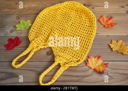 Borsa a corda gialla su sfondo di legno con foglie d'autunno intorno. Concetto di zero sprechi. Foto Stock