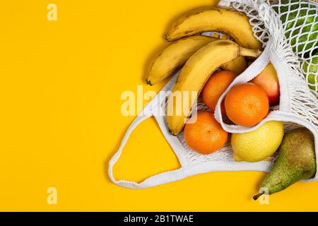 Concetto di assenza di rifiuti in plastica. Frutta fresca in un sacchetto di rete di maglia, vista dall'alto con copyspace. Borsa da shopping in mesh con frutta. Stile di vita sostenibile Foto Stock