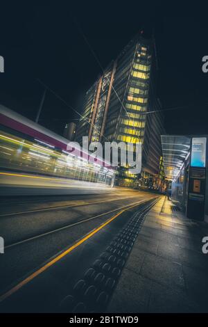Una lunga esposizione di un tram alla fermata del tram St Chads a Birmingham, Regno Unito, di notte Foto Stock