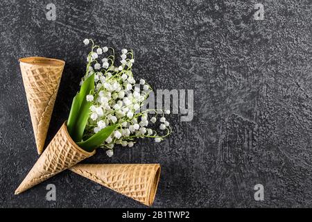 Cono gelato con gigli della valle. Vista dall'alto. Spazio di copia. Concetto di fiori primaverili. Foto Stock