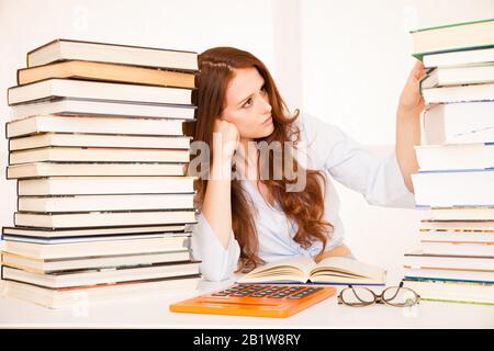 attraente giovane donna studia wtih hugr libro mucchi sulla sua scrivania Foto Stock