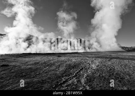 Tre geyser e un flusso di acqua calda emettono colonne di vapore all'alba, El Tatio Geyser Field, Andes Mountains, deserto di Atacama, Cile Foto Stock