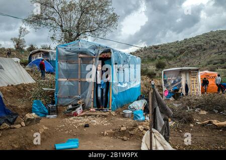 Lesbo, Grecia. 27th Feb, 2020. Un migrante è in piedi in una tenda in un campo temporaneo vicino al campo per i migranti a Moria. A seguito di gravi scontri tra polizia e abitanti arrabbiati dell'isola greca di Lesbo, che ha lasciato decine di feriti, il primo ministro Mitsotakis ha ordinato alla polizia antisommossa di ritirarsi dalle isole. Credito: Angelos Tzortzinis/Dpa/Dpa/Alamy Live News Foto Stock