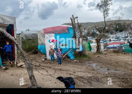 Lesbo, Grecia. 27th Feb, 2020. Una donna migrante sta con i suoi figli accanto a una tenda in un campo temporaneo vicino al campo per i migranti a Moria. A seguito di gravi scontri tra polizia e abitanti arrabbiati dell'isola greca di Lesbo, che ha lasciato decine di feriti, il primo ministro Mitsotakis ha ordinato alla polizia antisommossa di ritirarsi dalle isole. Credito: Angelos Tzortzinis/Dpa/Dpa/Alamy Live News Foto Stock