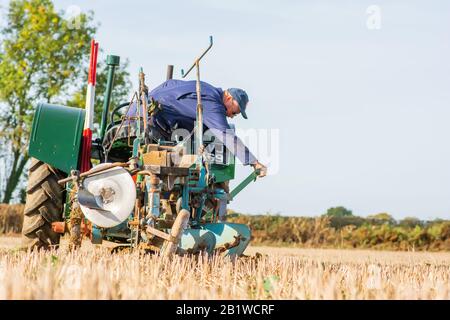 Piccolo trattore verde vintage contadino plowig il solco in un campo in fattoria nel Berkshire Inghilterra 2018 Foto Stock