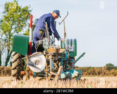 Piccolo trattore verde vintage contadino plowig il solco in un campo in fattoria nel Berkshire Inghilterra 2018 Foto Stock