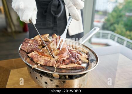 Il cameriere sta macellando con un coltello. Vari set di carne alla griglia. Menu ristorante barbecue, una serie di foto di carni diverse. Foto Stock