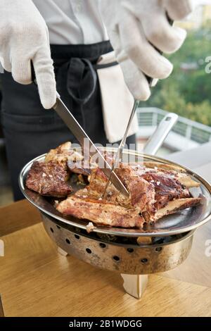 Il cameriere sta macellando con un coltello. Vari set di carne alla griglia. Menu ristorante barbecue, una serie di foto di carni diverse. Foto Stock