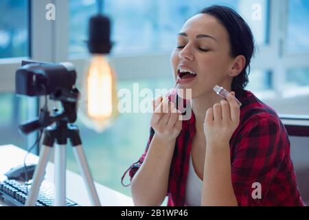 Dare consigli. Vista dall'alto di una bella giovane donna che tiene spazzola per il trucco e sorridente mentre fa video sui social media Foto Stock