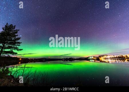 Aurora brilla attraverso la linea appena sopra l'orizzonte, stelle che riflettono al lago, notte la campagna scandinava, autunno Foto Stock