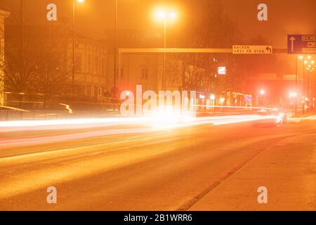 Luci colorate e sfocate, tracce del traffico notturno intenso sulla strada della città di Umea, tempo foggy autunno, Svezia Foto Stock