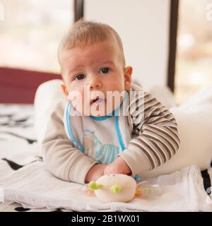 bambino di 3 mesi gioca con i suoi giocattoli e guarda la fotocamera Foto Stock