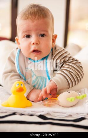 bambino di 3 mesi gioca con i suoi giocattoli e guarda la fotocamera Foto Stock