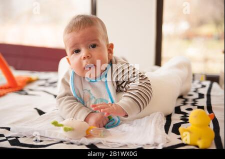 bambino di 3 mesi gioca con i suoi giocattoli e guarda la fotocamera Foto Stock