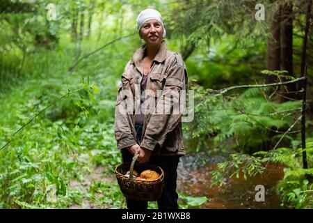 Una donna con un cesto di funghi nel bosco. Foto Stock