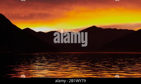 Lago d'Iseo, Pisogne, Brescia, Italia - 26 dic 2020: Tramonto d'arancio scuro sul Lago d'Iseo in riva Pisogne Foto Stock