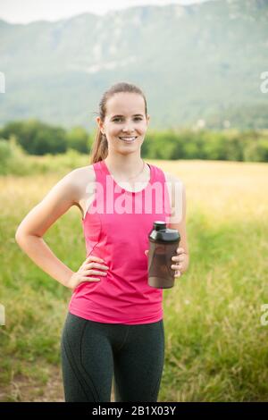 Bella giovane donna riposa dopo un allenamento a lungo termine all'aperto nella natura Foto Stock