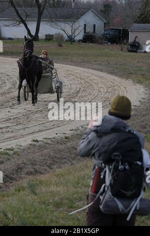 Milford, Delaware, Stati Uniti. 27th Feb, 2020. Dave WHITSON galles ad un addestratore che esercita un cavallo di corsa su una pista vicino all'autostrada rurale fra Milford, DE e Denton, MD. Whitson, un insegnante di storia delle scuole superiori di Portland, Oregon, sta camminando per incontrare e parlare con la gente lungo il suo percorso per capire meglio e collegare l'America rurale. Foto Stock