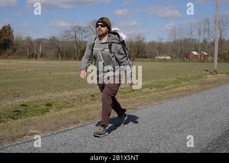 Milford, Delaware, Stati Uniti. 27th Feb, 2020. Dave WHITSON entra in un headwind segnalato per essere 20 miglia all'ora lungo una strada pavimentata rurale fra Milford, DE e Denton, MD il 27 febbraio 2020. Whitson, un insegnante di storia delle scuole superiori di Portland, Oregon, sta camminando per incontrare e parlare con le persone lungo il suo percorso per capire meglio e connettersi con l'America rurale. Foto Stock