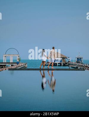 Coppia in vacanza di lusso in Thailandia, uomini e donne piscina infinity che si affaccia sul mare Foto Stock