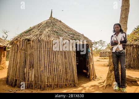 Un ragazzo di Hausa/Fulani posa per la foto di fronte a una casa di paglia in un villaggio di Abuja, Nigeria. Foto Stock