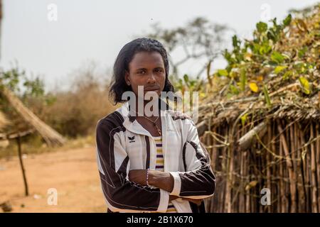 Un ragazzo di Hausa/Fulani posa per la foto di fronte a una casa di paglia in un villaggio di Abuja, Nigeria. Foto Stock