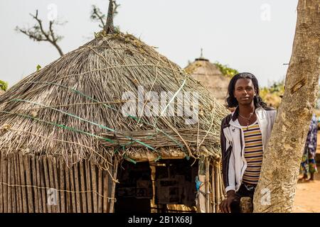 Un ragazzo di Hausa/Fulani posa per la foto di fronte a una casa di paglia in un villaggio di Abuja, Nigeria. Foto Stock