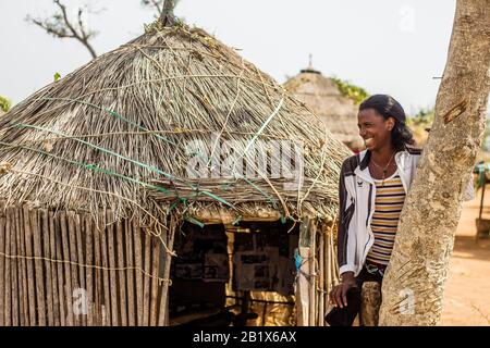 Un ragazzo di Hausa/Fulani posa per la foto di fronte a una casa di paglia in un villaggio di Abuja, Nigeria. Foto Stock