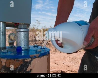 La candeggina viene versata in Una testa Di Pozzo per pulire i detriti organici dal tubo e dal rotore della pompa. Foto Stock