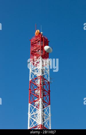 Antenna torre di trasmissione., dipinto di bianco e rosso in un giorno di cielo blu chiaro. Foto Stock